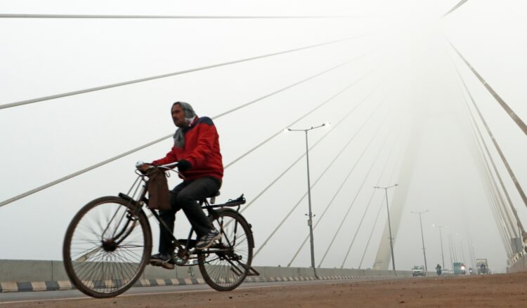New Delhi: A man paddles the cycle as he passes through Signature bridge on a cold and foggy morning in New Delhi on Tuesday, December 27, 2022. (Photo: IANS/Wasim Sarvar)