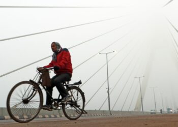 New Delhi: A man paddles the cycle as he passes through Signature bridge on a cold and foggy morning in New Delhi on Tuesday, December 27, 2022. (Photo: IANS/Wasim Sarvar)