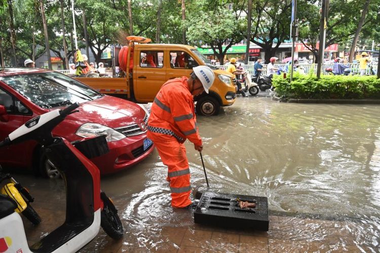 (240519) -- NANNING, May 19, 2024 (Xinhua) -- A sanitary worker cleans up sewerage facilities on a street in Nanning, south China's Guangxi Zhuang Autonomous Region, May 19, 2024. Heavy rain hit Nanning on Saturday. (Xinhua/Lu Boan)
