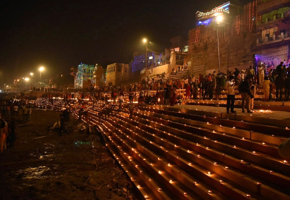 Varanasi:Devotees light earthen lamps on the bank of River Ganga during Dev Deepawali Festival in Varanasi on Friday November 19,2021.(PHOTO:IANS)