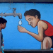 Mumbai: Two boys walk past a graffiti wall depicting a boy drinking water from a tap on the eve of World Water Day, in Mumbai on Tuesday, March 21, 2023. (Photo:IANS)