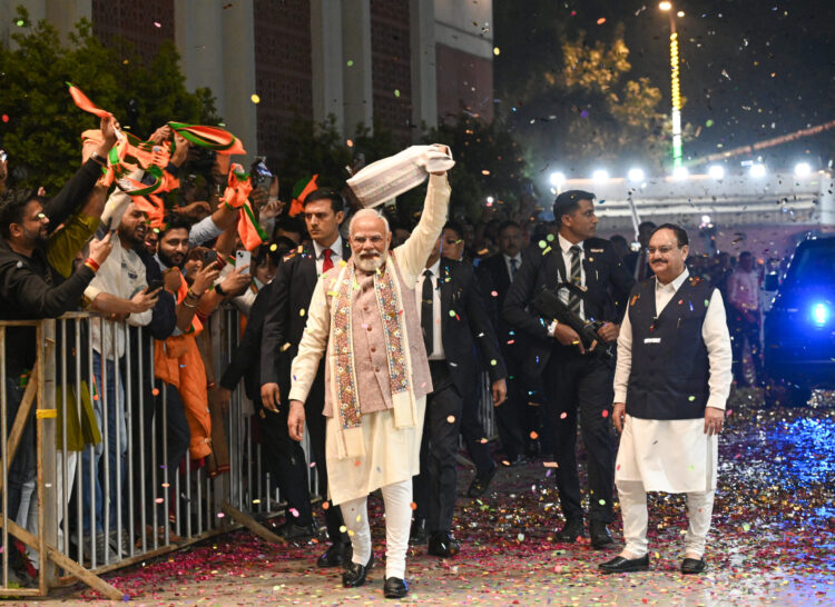 New Delhi: Prime Minister Narendra Modi waves a "gamcha" as he arrives during the celebration of NDAs victory in the Bihar Assembly elections, at BJP headquarters, in New Delhi, Friday, Nov. 14, 2025. Union Health Minister and BJP National President JP Nadda is also seen. (IANS)