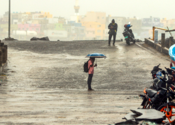 Chennai: A man holds an umbrella while braving strong winds at Marina Beach ahead of Cyclone Ditwah’s landfall in Chennai on Sunday, November 30, 2025. (Photo: IANS)