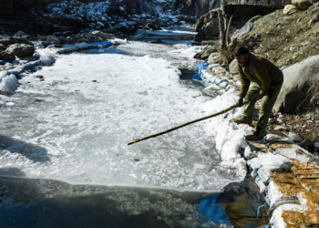 Baramulla: A man tries to break the ice on a stream completely frozen after the minimum temperature dropped to a record low of minus 6 degrees Celsius, at the Drung area of Tangmarg in Baramulla district, north Kashmir, on Tuesday, January 13, 2026. (Photo: IANS)