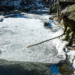 Baramulla: A man tries to break the ice on a stream completely frozen after the minimum temperature dropped to a record low of minus 6 degrees Celsius, at the Drung area of Tangmarg in Baramulla district, north Kashmir, on Tuesday, January 13, 2026. (Photo: IANS)