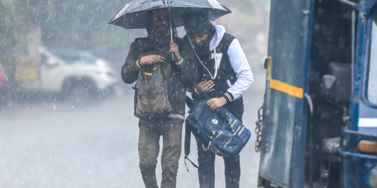 Noida: Commuters walk along a road holding an umbrella during sudden rainfall in the cold season, in Noida, Uttar Pradesh on Tuesday, January 27, 2026. (Photo: IANS)